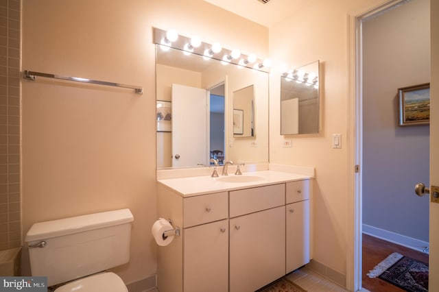 bathroom with vanity, baseboards, and toilet