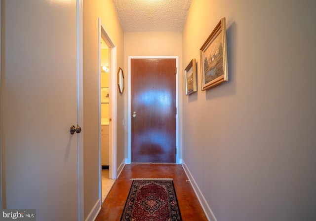 doorway to outside with a textured ceiling, baseboards, and finished concrete floors