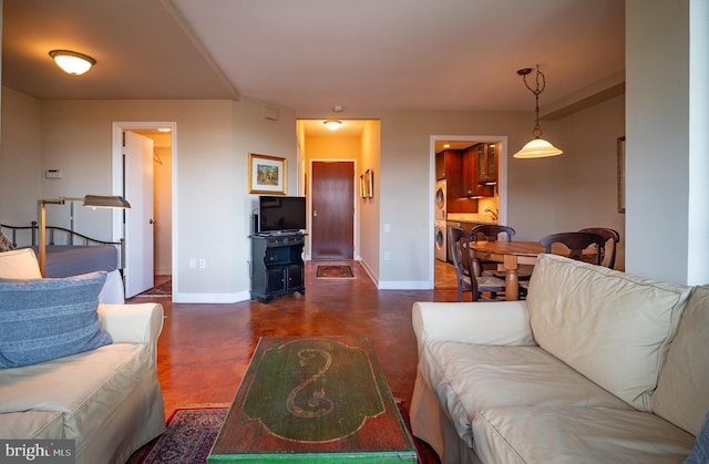 living area with baseboards, concrete floors, and washer / dryer