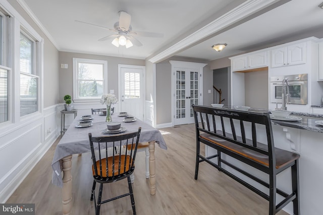 dining area with french doors, crown molding, light wood-style flooring, and ceiling fan
