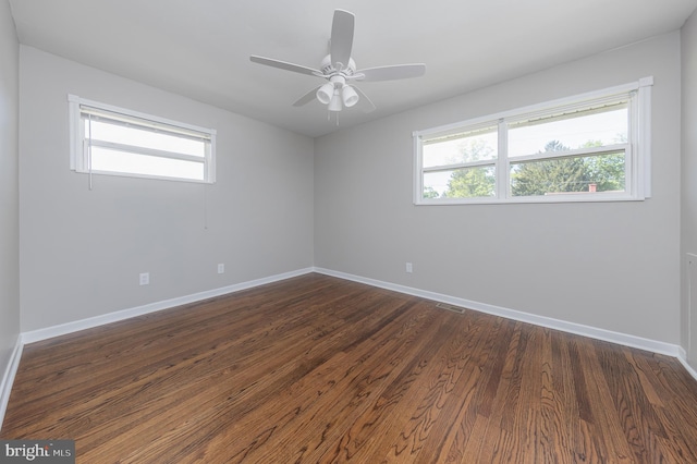 unfurnished room with baseboards, plenty of natural light, dark wood-style flooring, and visible vents