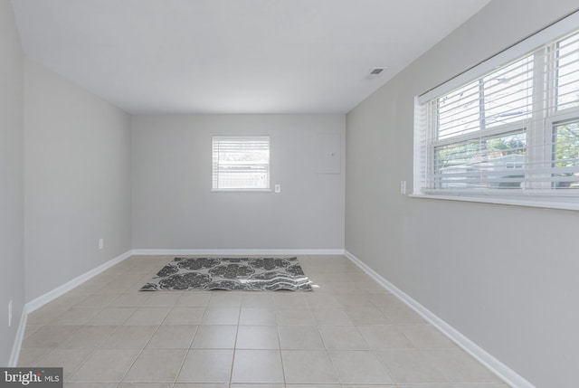 spare room featuring baseboards, light tile patterned flooring, and visible vents