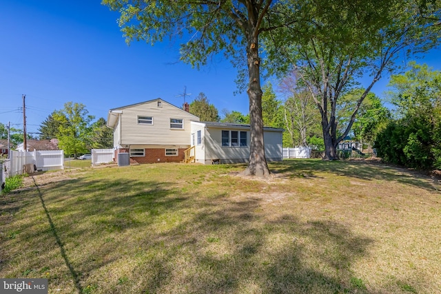 back of property featuring fence, central AC unit, a chimney, and a lawn