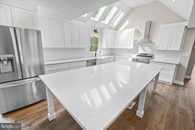 7746 Emerson Burrier Rd, Mount Airy, MD 21771 - kitchen featuring appliances with stainless steel finishes, a center island, white cabinetry, light stone counters, and wall chimney exhaust hood