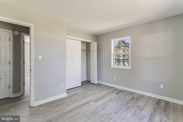 unfurnished bedroom featuring baseboards, a closet, and wood finished floors