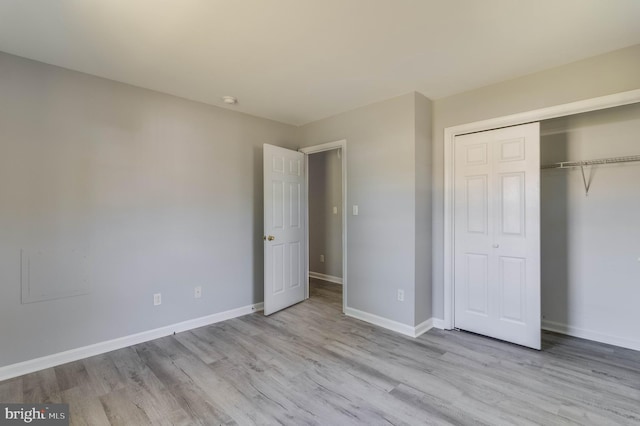unfurnished bedroom with baseboards, wood finished floors, and a closet