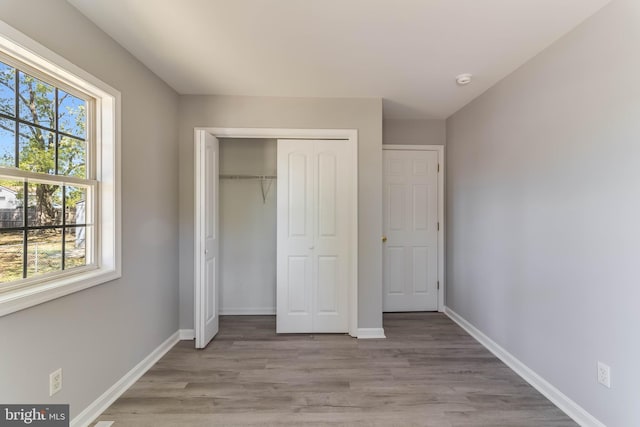 unfurnished bedroom with baseboards, a closet, and wood finished floors