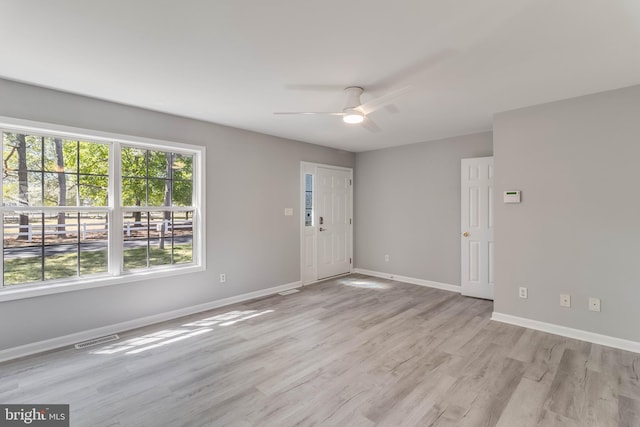 interior space featuring visible vents, a ceiling fan, light wood finished floors, and baseboards
