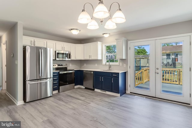 kitchen featuring light wood-style floors, blue cabinetry, appliances with stainless steel finishes, a sink, and an inviting chandelier