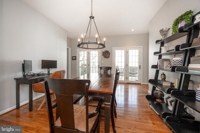 dining area with light wood finished floors, an inviting chandelier, baseboards, and french doors
