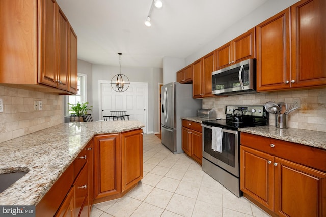 kitchen featuring light tile patterned floors, brown cabinetry, a notable chandelier, appliances with stainless steel finishes, and tasteful backsplash