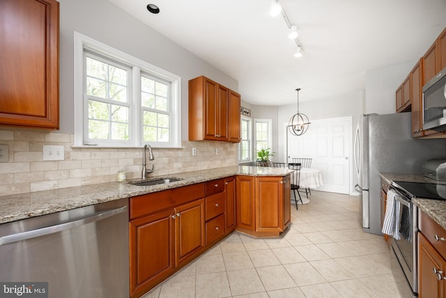 kitchen featuring light tile patterned floors, a sink, stainless steel appliances, backsplash, and light stone counters