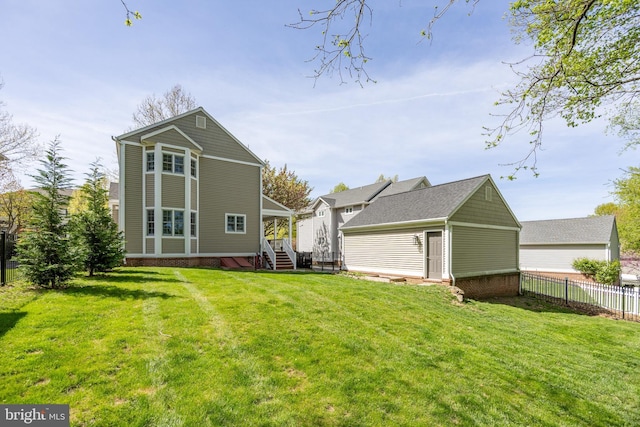 back of house featuring a yard, an outdoor structure, and fence