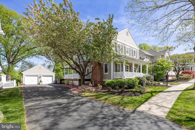 view of front of house with covered porch, a garage, fence, aphalt driveway, and an outbuilding