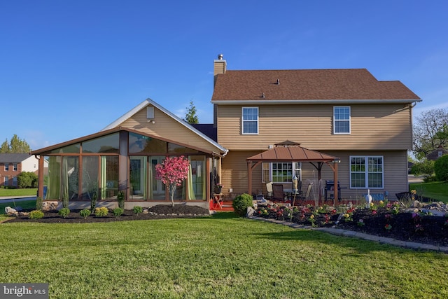 back of house with a gazebo, a sunroom, a chimney, a patio, and a yard