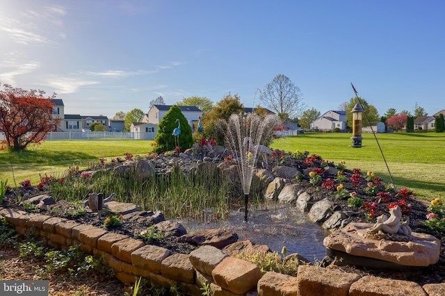 view of yard featuring a garden pond, fence, and a residential view