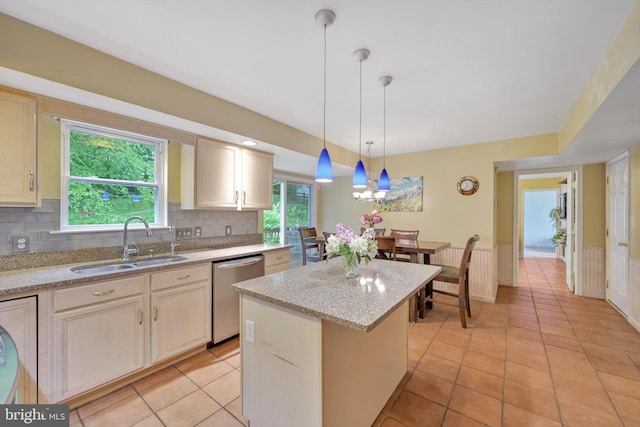 kitchen with stainless steel dishwasher, a sink, a center island, tasteful backsplash, and light tile patterned flooring