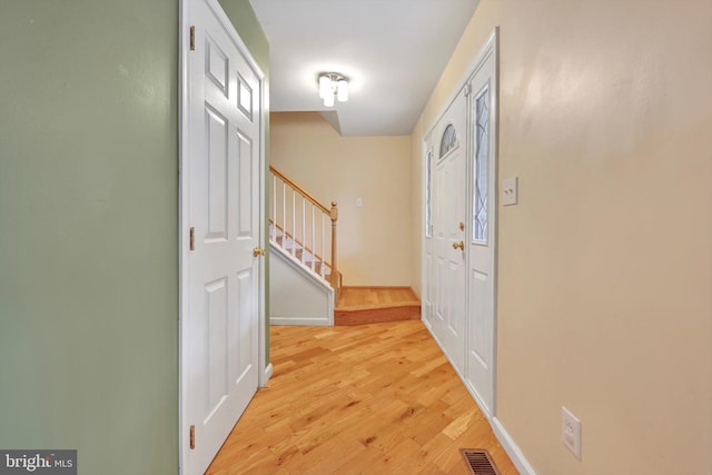 entryway with stairs, light wood finished floors, and baseboards