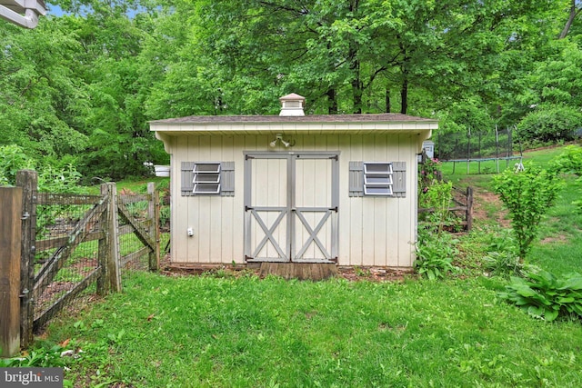 view of shed featuring a trampoline and a gate