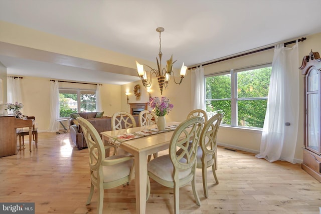dining space featuring light wood-type flooring, a chandelier, and baseboards