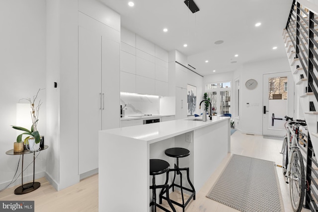 kitchen with modern cabinets, recessed lighting, light countertops, white cabinetry, and a sink