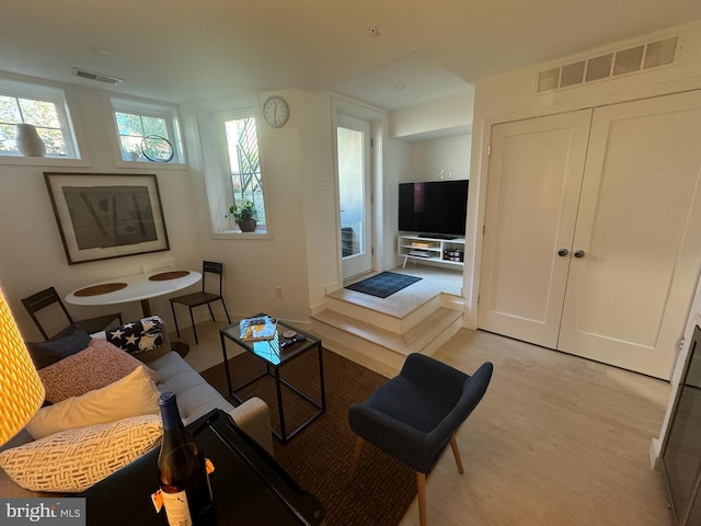 living room featuring visible vents, plenty of natural light, and light wood-style flooring