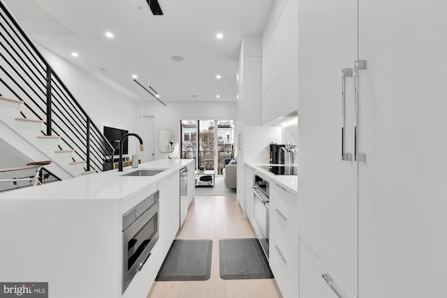 kitchen featuring a sink, stainless steel appliances, white cabinetry, recessed lighting, and modern cabinets