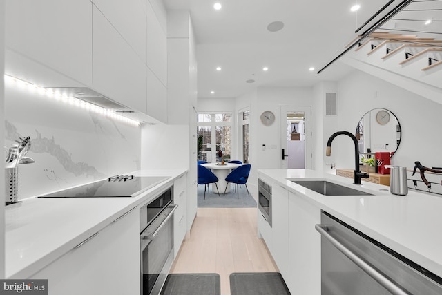 kitchen with white cabinets, appliances with stainless steel finishes, a sink, recessed lighting, and modern cabinets