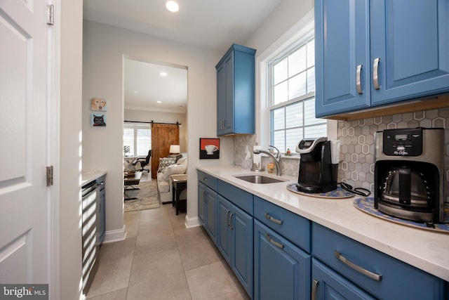 kitchen with blue cabinets, a sink, decorative backsplash, and light countertops