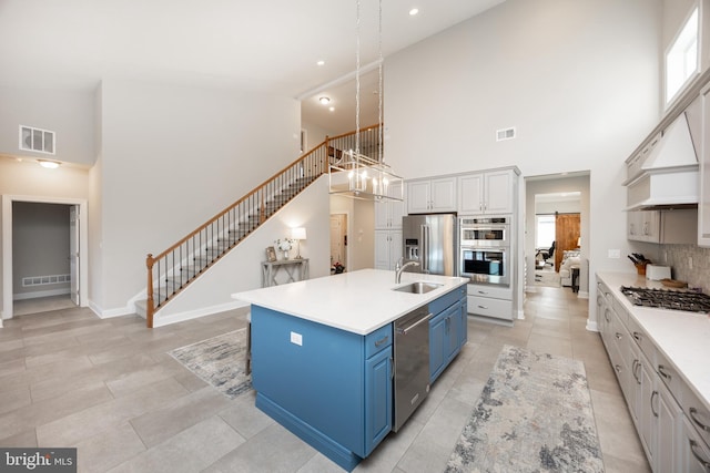 kitchen with a sink, a high ceiling, stainless steel appliances, and blue cabinets