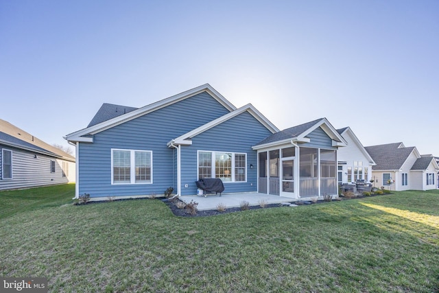 rear view of house with a lawn, a patio, and a sunroom