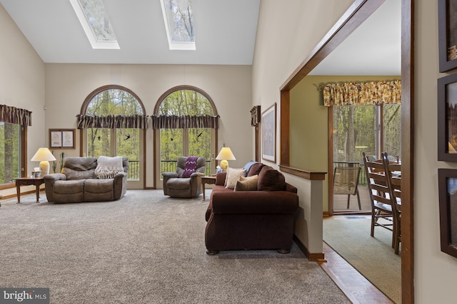 living area with carpet floors, high vaulted ceiling, and a skylight