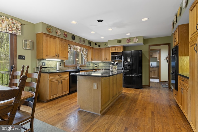 kitchen with dark countertops, decorative backsplash, black appliances, and dark wood-type flooring