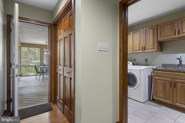 laundry room featuring cabinet space, washer / dryer, a sink, and light wood-type flooring