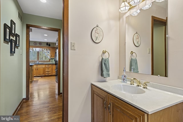 bathroom with vanity, recessed lighting, baseboards, wood finished floors, and visible vents