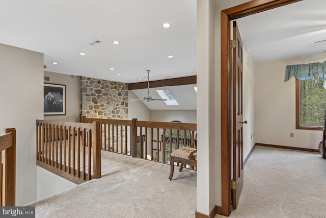 hall featuring carpet floors, visible vents, baseboards, lofted ceiling with skylight, and recessed lighting
