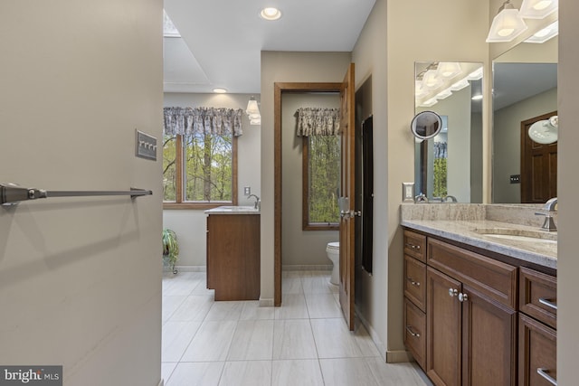 bathroom with toilet, baseboards, tile patterned flooring, and vanity