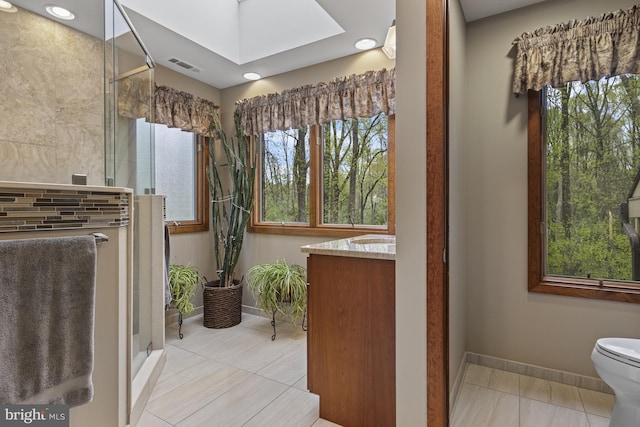 bathroom with a skylight, plenty of natural light, baseboards, and a stall shower