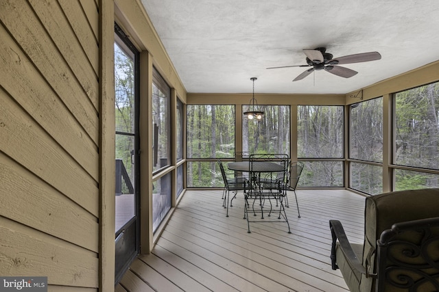 sunroom featuring outdoor dining area, ceiling fan, and a wealth of natural light