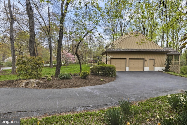 view of property exterior with a garage, aphalt driveway, and a yard