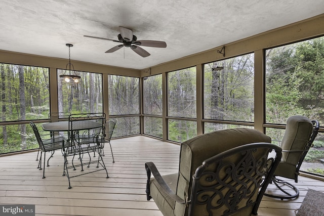sunroom featuring plenty of natural light, a ceiling fan, and outdoor dining space