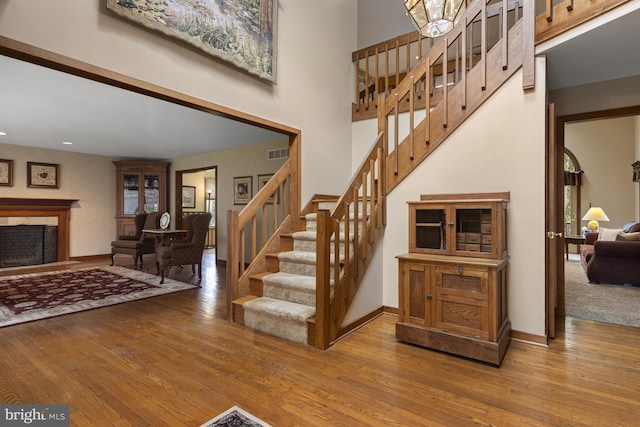 stairs featuring visible vents, baseboards, wood finished floors, and a fireplace