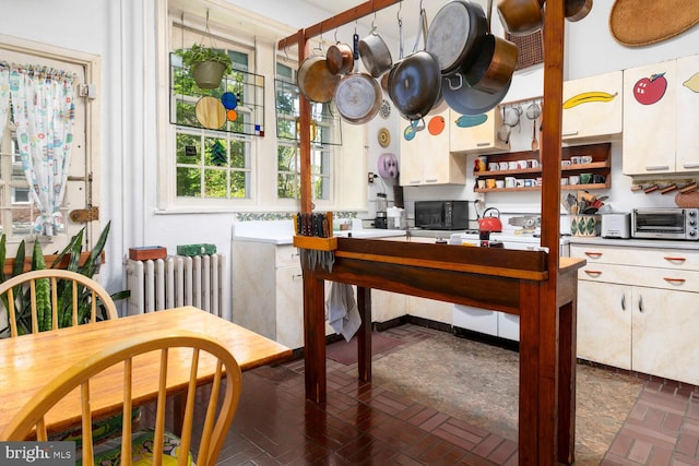 kitchen featuring brick floor, open shelves, black microwave, and radiator