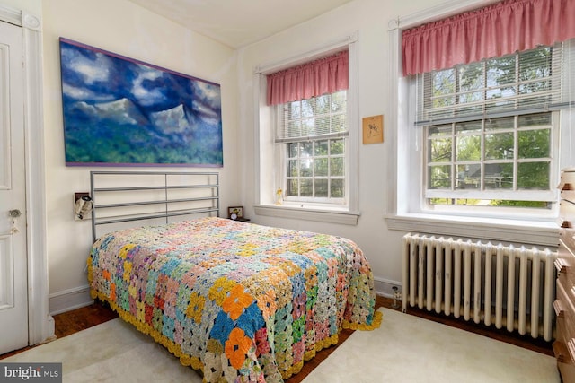 bedroom featuring wood finished floors, baseboards, and radiator heating unit