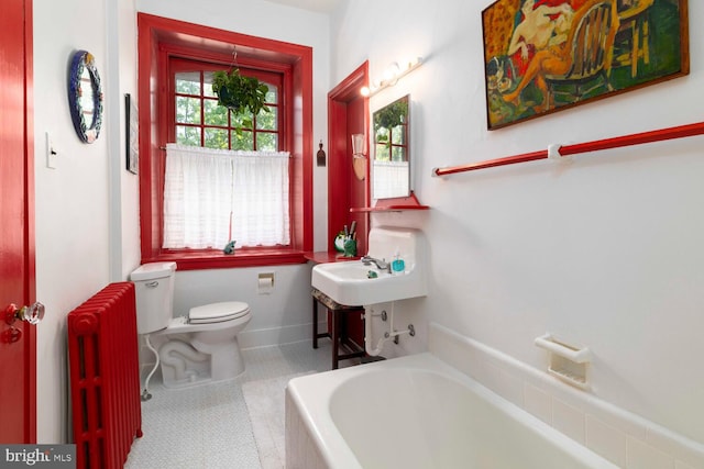 full bath featuring toilet, baseboards, radiator heating unit, tile patterned floors, and a bathing tub