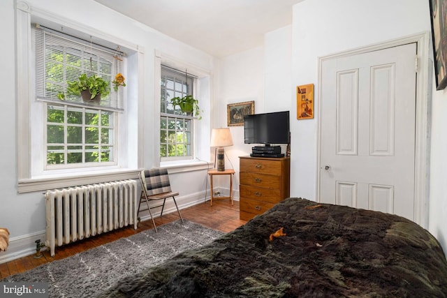 bedroom with baseboards, radiator, and wood finished floors
