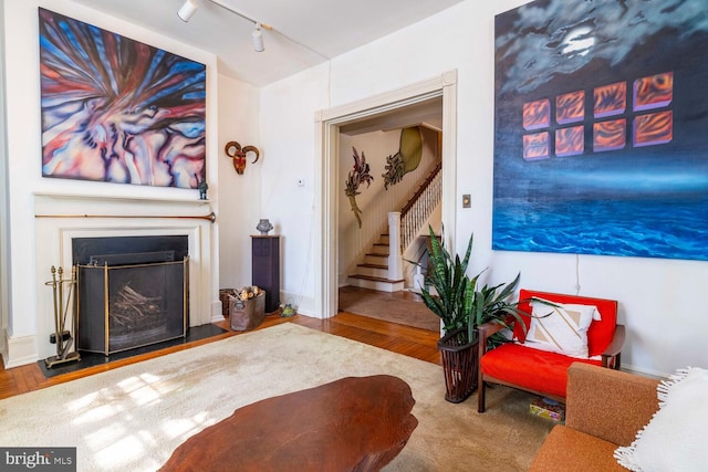 living room featuring stairs, rail lighting, wood finished floors, and a fireplace