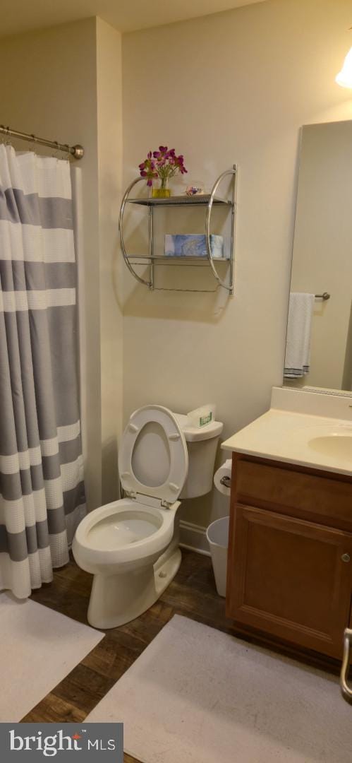 24840 Mistletoe Dr, Georgetown, DE 19947 - bathroom with a shower with shower curtain, toilet, wood finished floors, and vanity