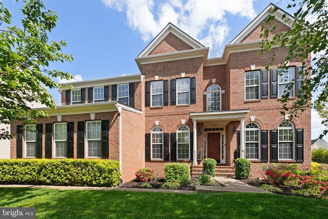 colonial house featuring a front yard and brick siding