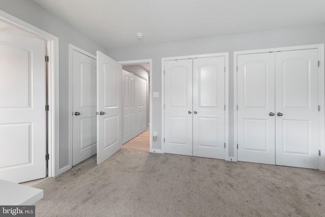unfurnished bedroom featuring carpet floors and two closets